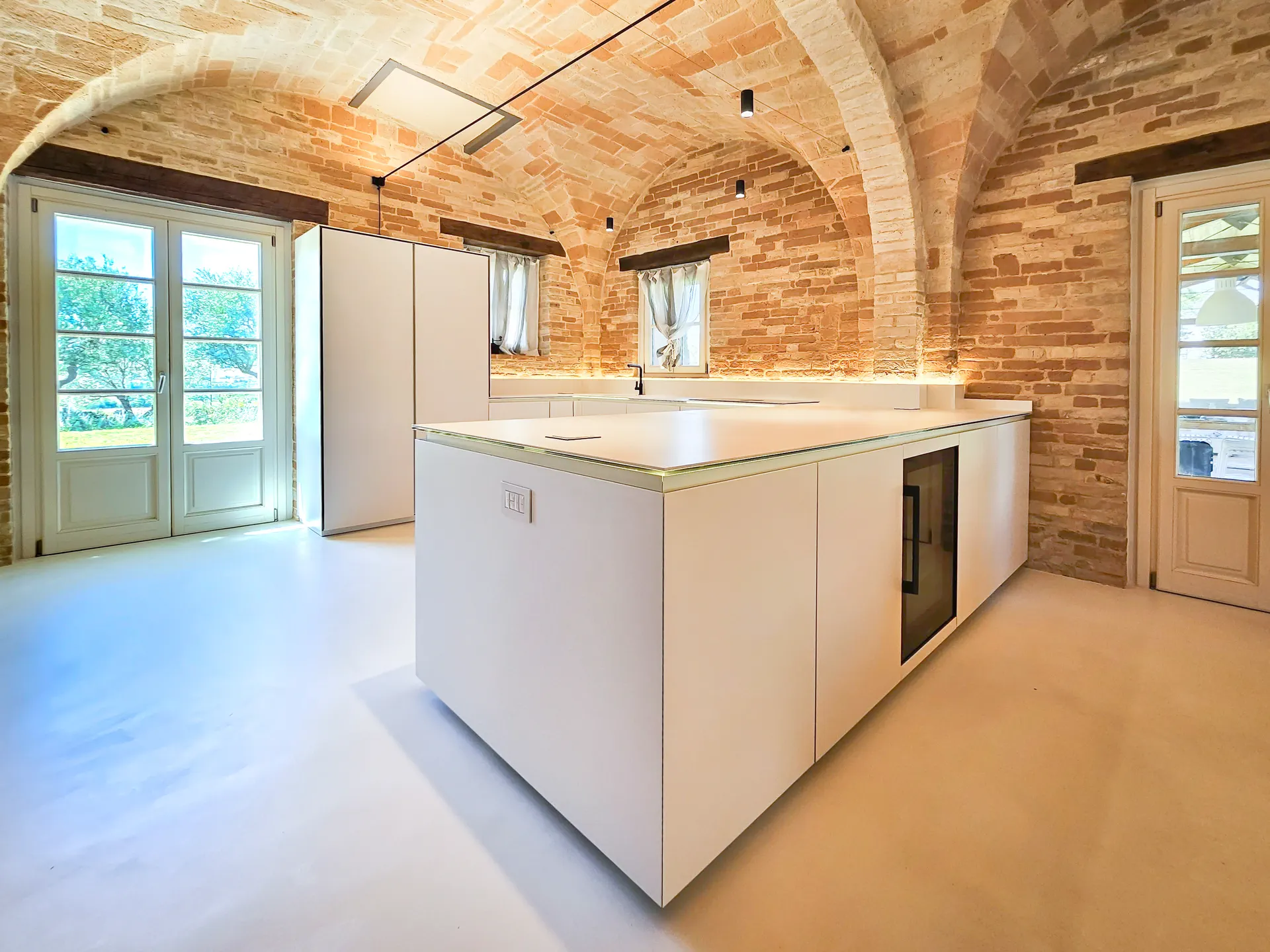 Isola da cucina con piano in gres sotto una volta in mattoni